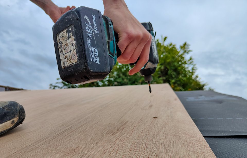 Screwing down roof insulation.